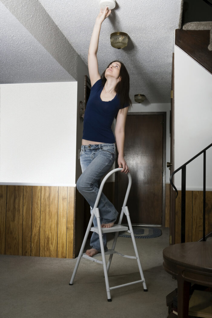 Woman testing smoke alarm